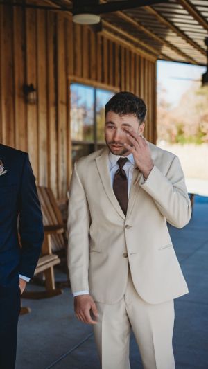 An emotional moment captured during a wedding as someone wipes away tears in a beige suit.