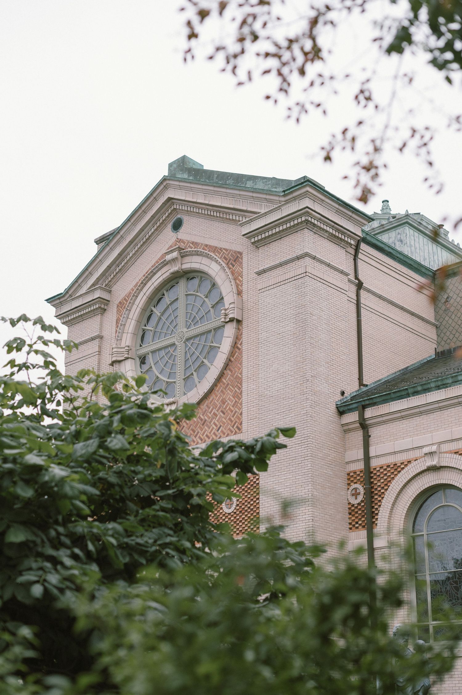 Exterior view of a historic pink brick church with arched windows and ornate architectural details.