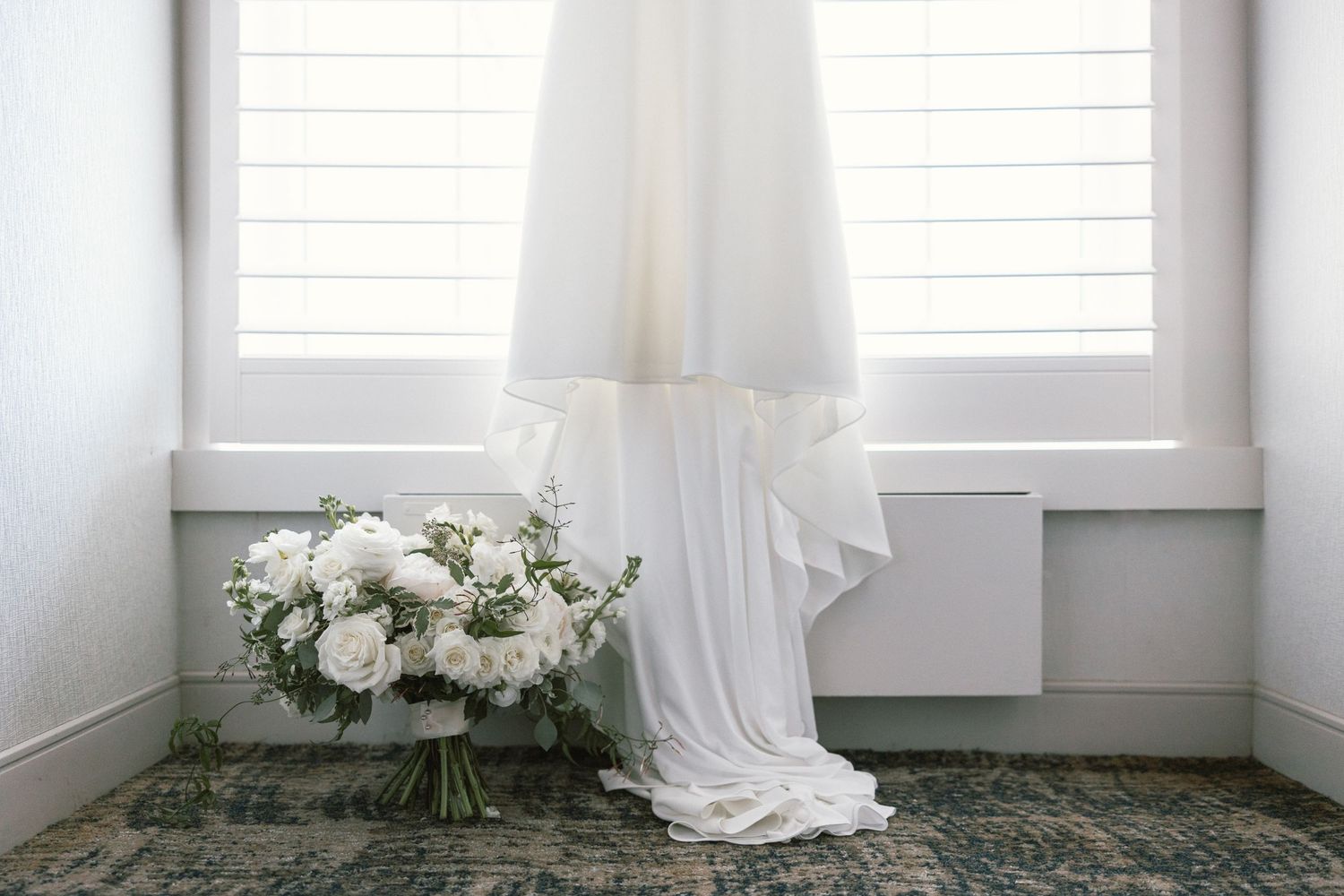 Minimalist white room interior with sunlit windows and delicate floral arrangements.