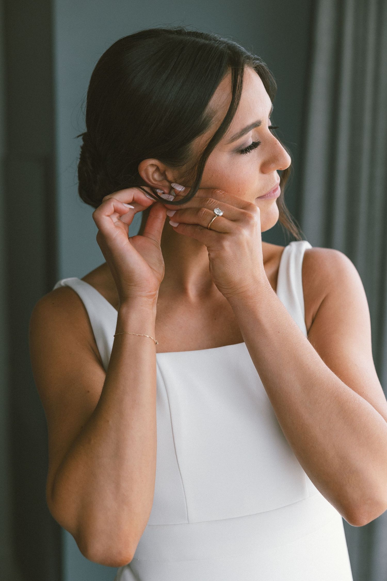 Sequential shots of someone in white adjusting their earrings while getting ready.