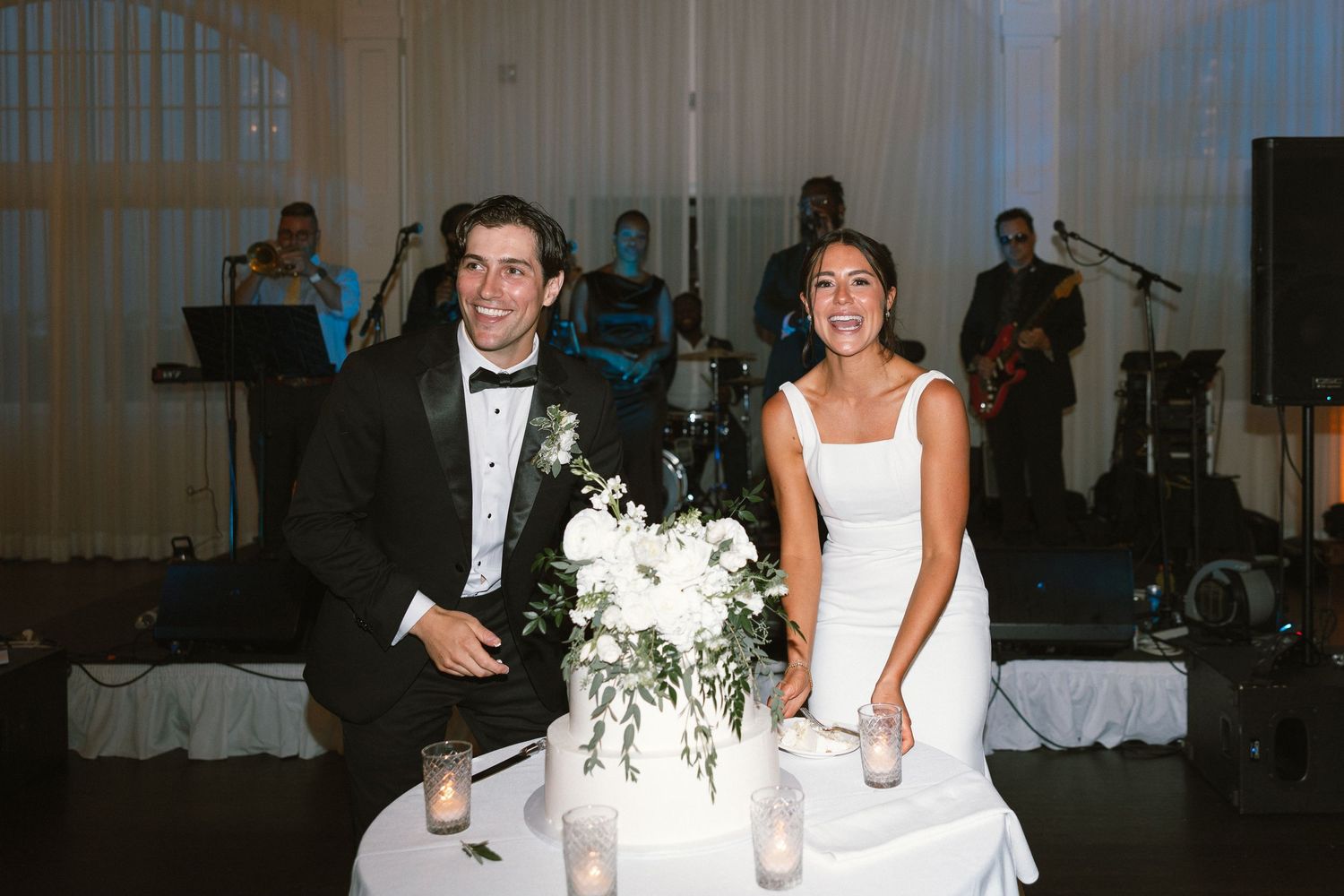 Wedding reception venue with elegant table settings and white floral arrangements.