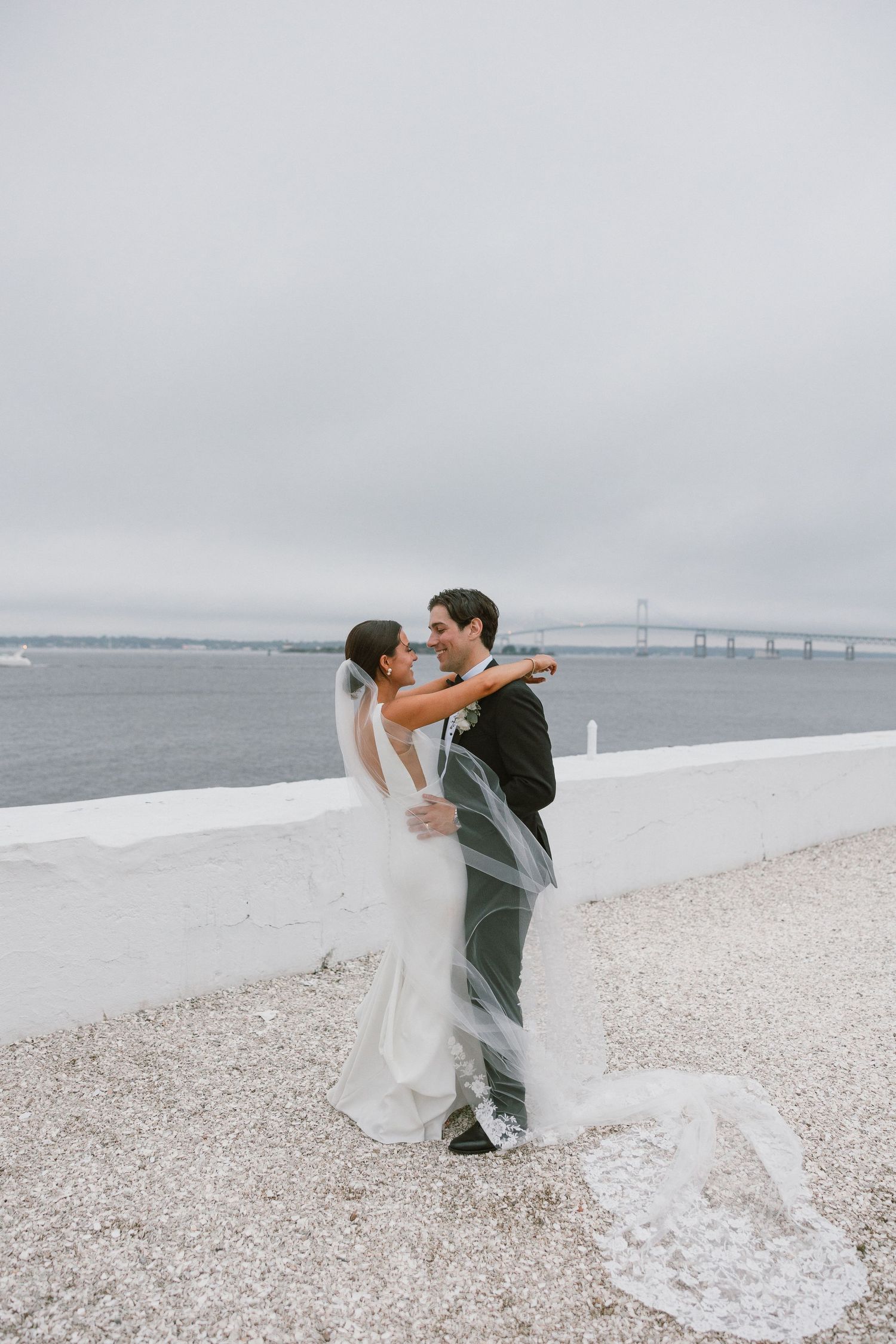 Couple dancing and twirling on a beach with flowing wedding dress and veil catching the wind.