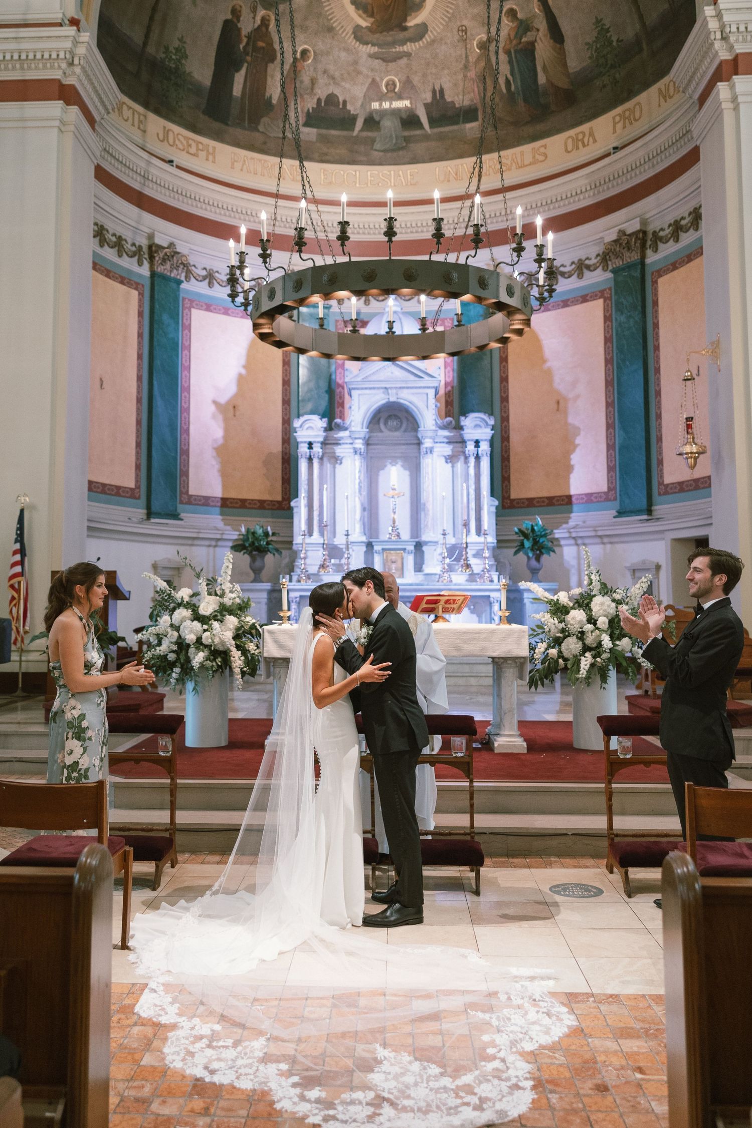 Wedding ceremony takes place in ornate church sanctuary with domed ceiling and decorative altar.