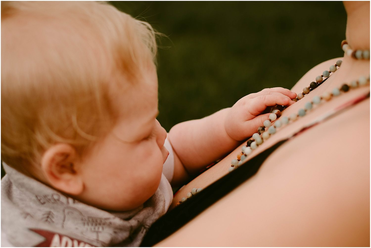 Close-up of a baby's hand reaching for a beaded necklace.