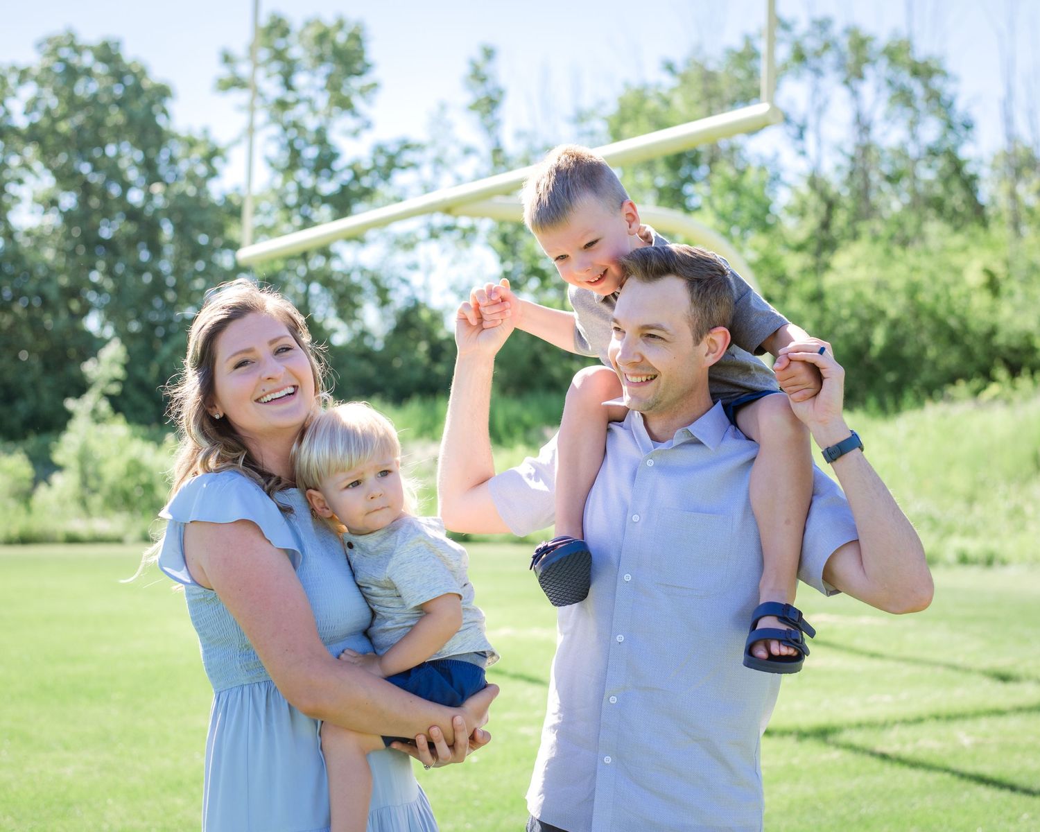 A family enjoys playtime together outdoors with toy planes in a green field.