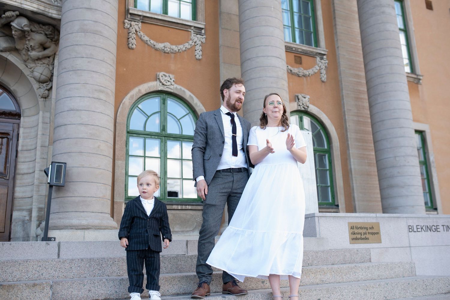Wedding party posing on grand stone steps of historic building with columns.