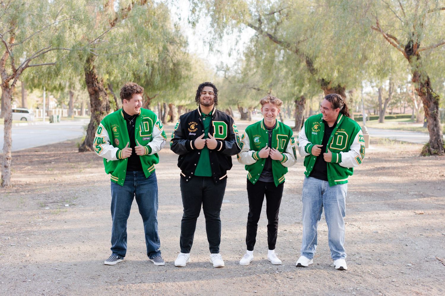 Senior football guys in letterman jackets outside hiking trail.