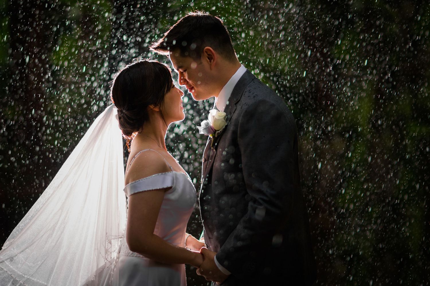 Romantic wedding moment captured in the rain with sparkles and droplets creating a magical atmosphere.