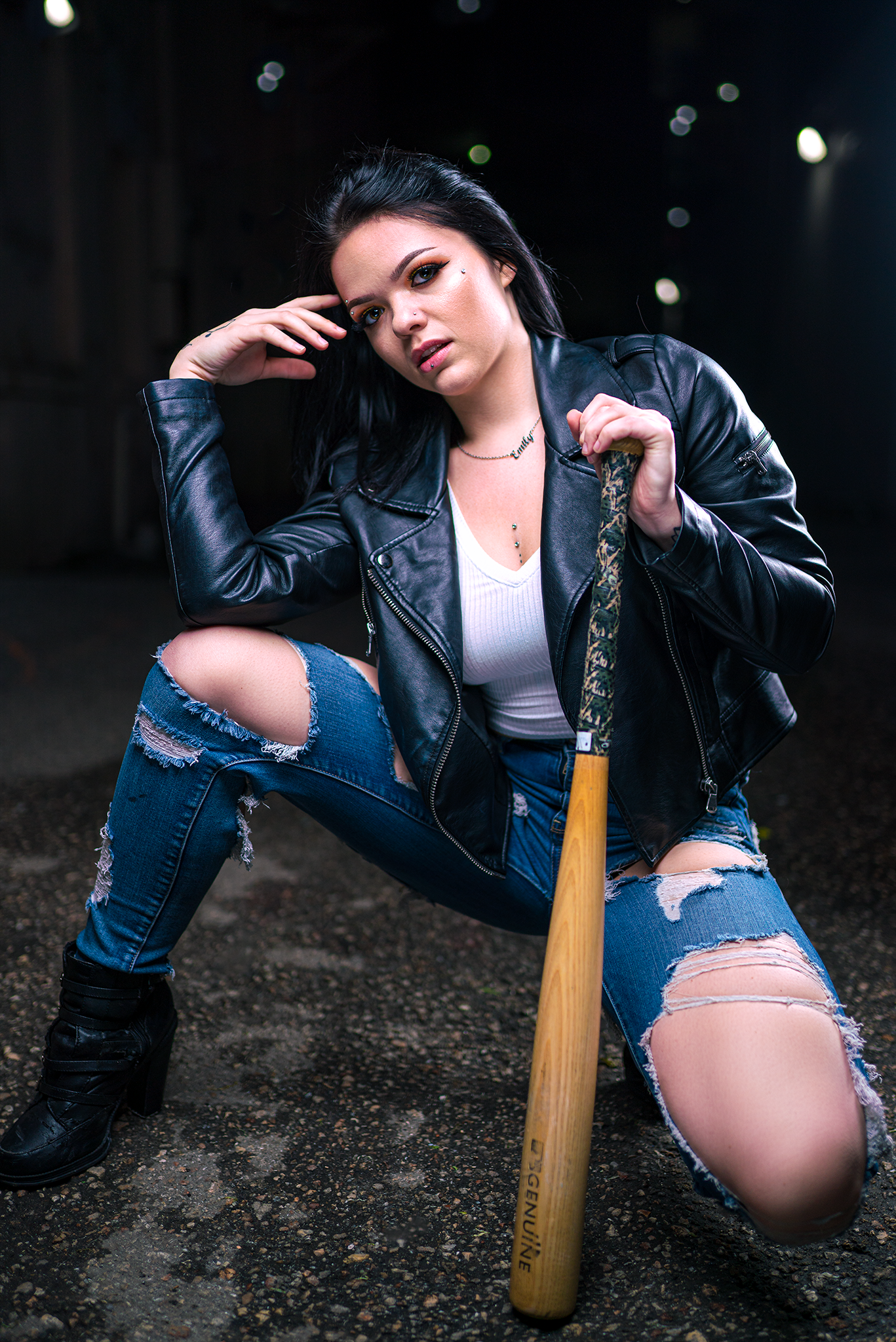 Edgy fashion portrait with leather jacket and baseball bat against dark urban background.