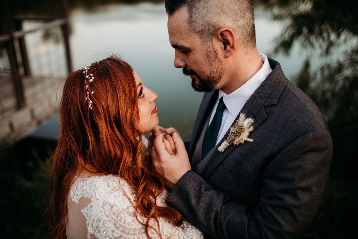 Intimate wedding portrait captured by water during golden hour with soft natural lighting.