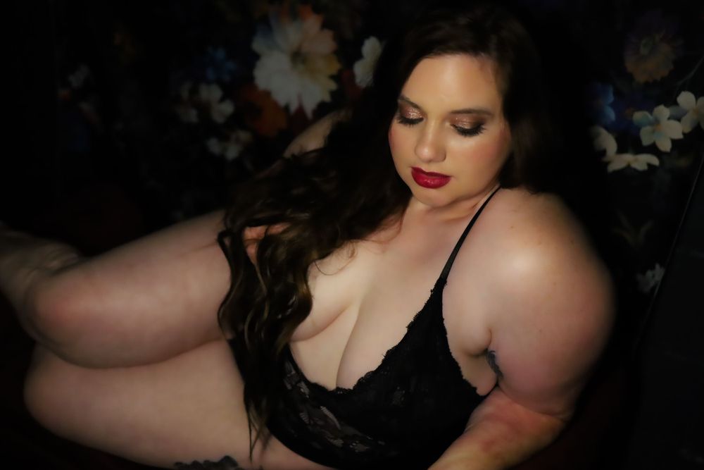 Artistic boudoir photo with dark floral background and black lace.