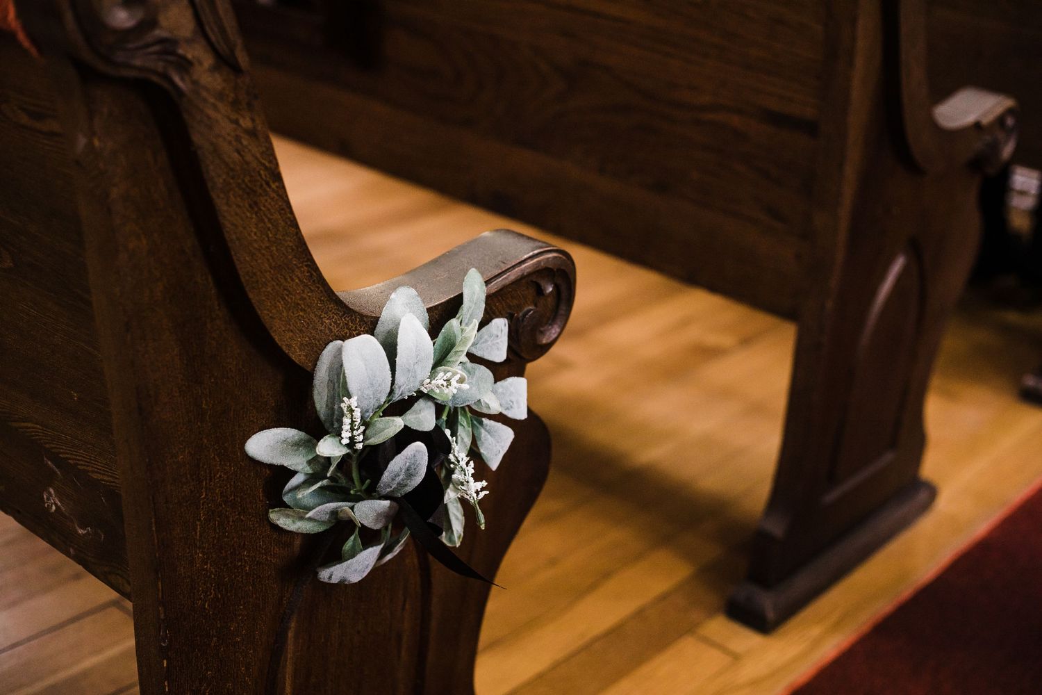 Wooden church pews with red carpet in traditional sanctuary.