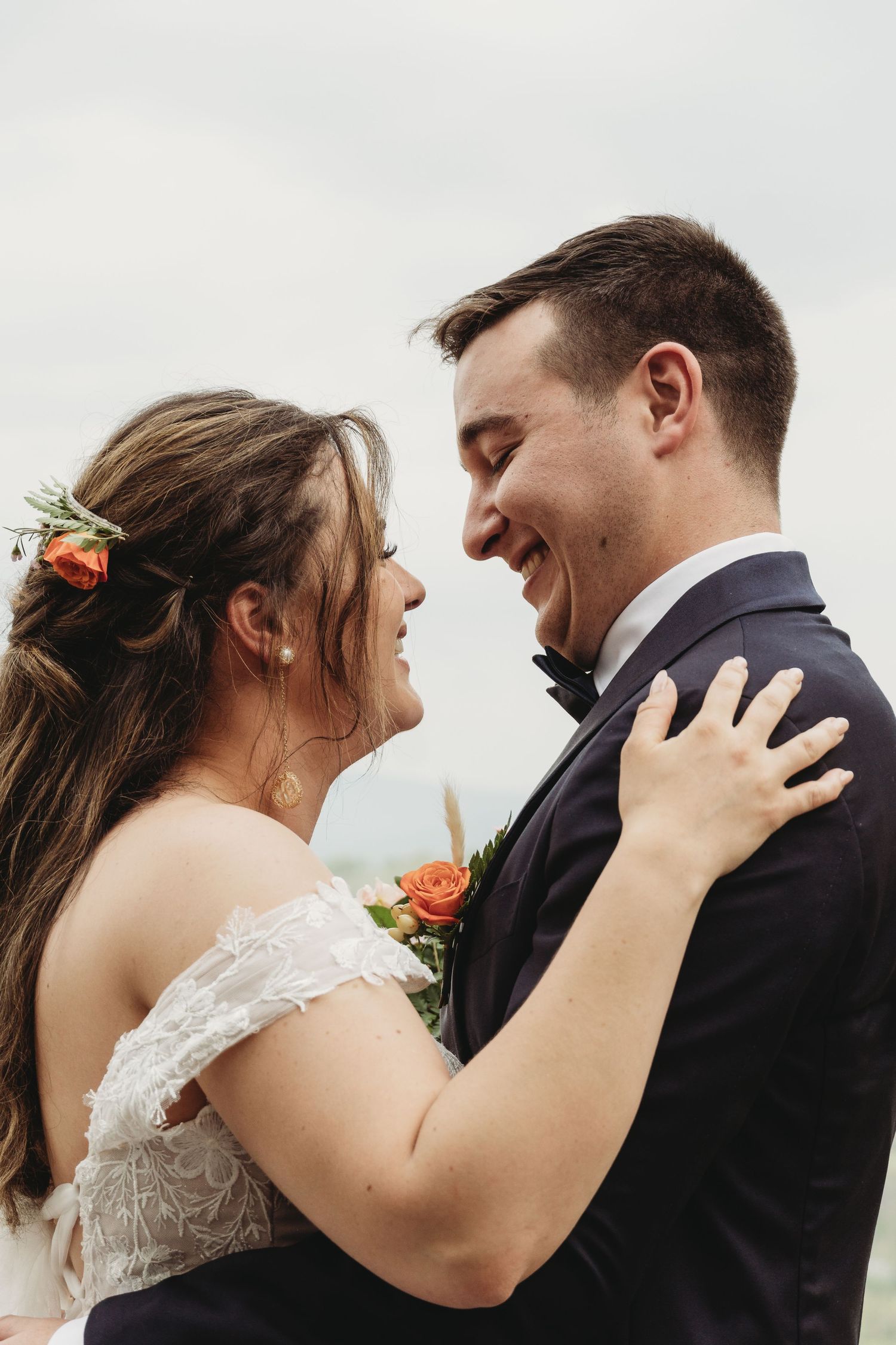 Joyful moment between newlyweds against cloudy mountain landscape.