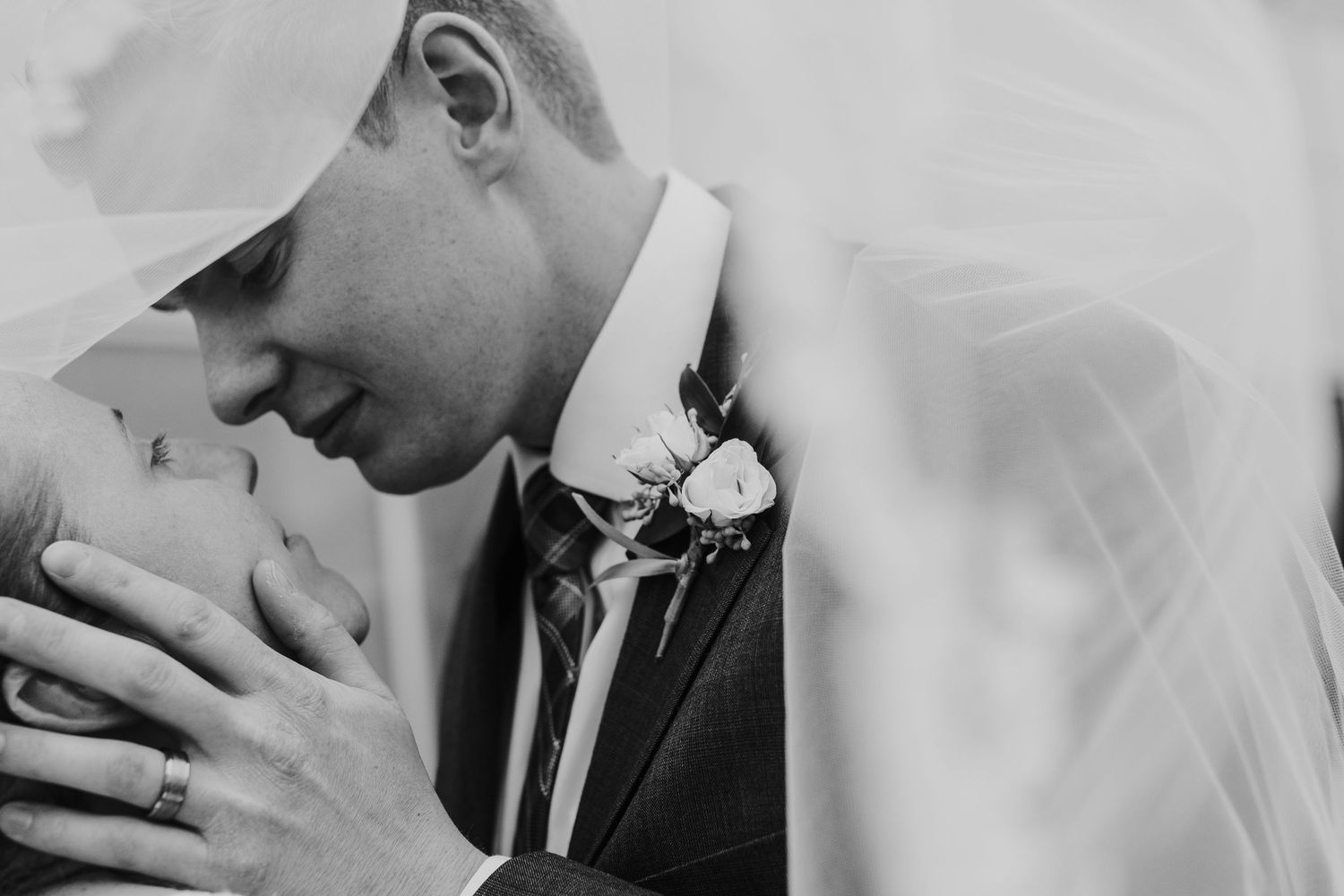 Black and white close-up photo of a romantic wedding kiss between newlyweds.