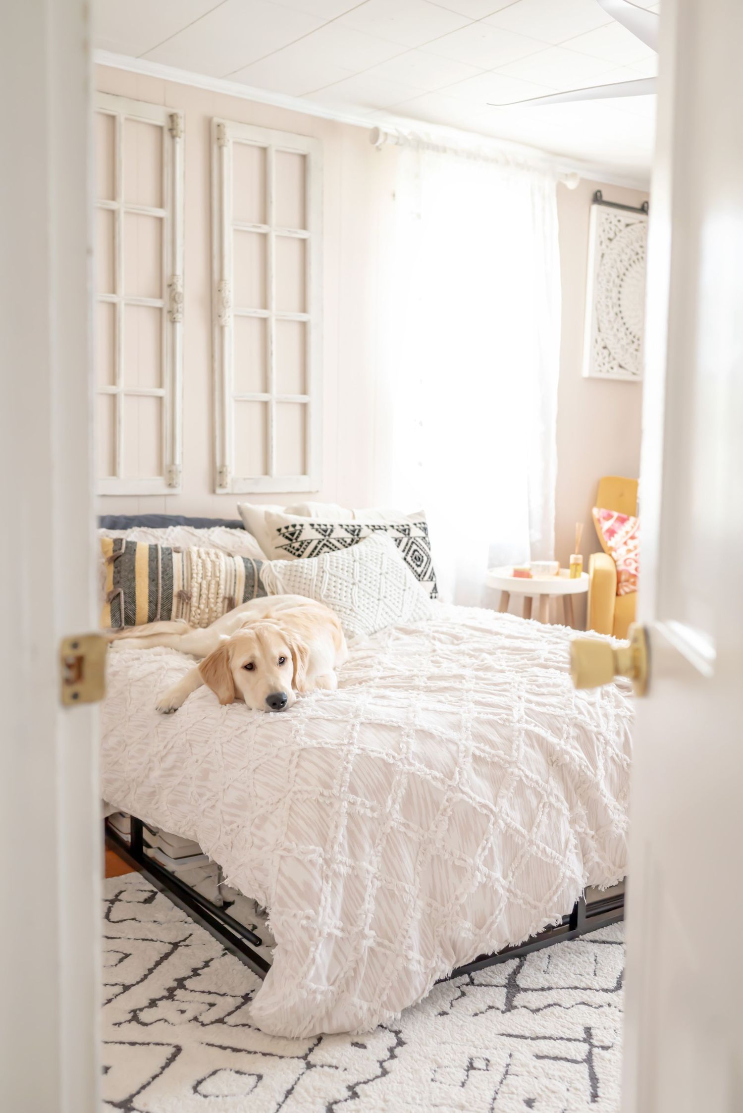Looking through doorway at a somber looking golden retriever laying on bed. In-home family session.  Doughman Photography