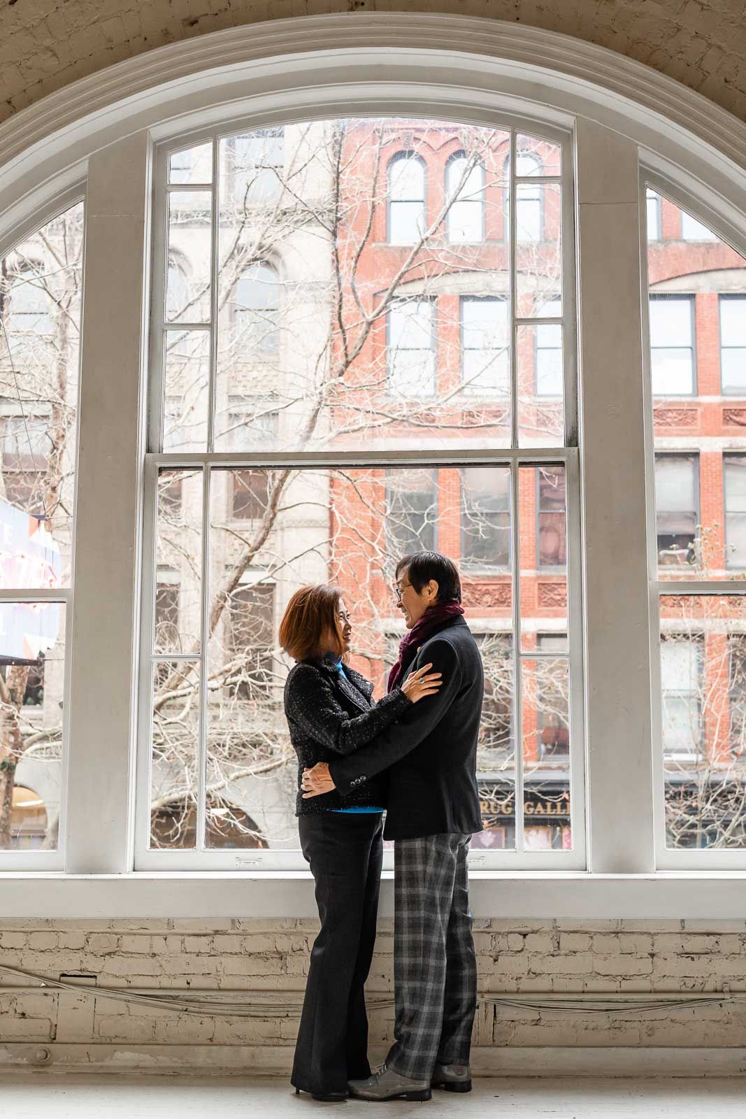 Couple smiling in front of a giant arched window in Seattle