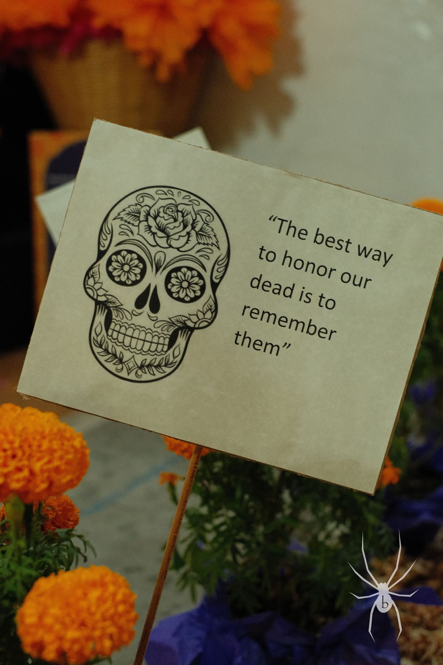 Sugar skull drawing with quote about remembering the dead surrounded by marigold flowers.