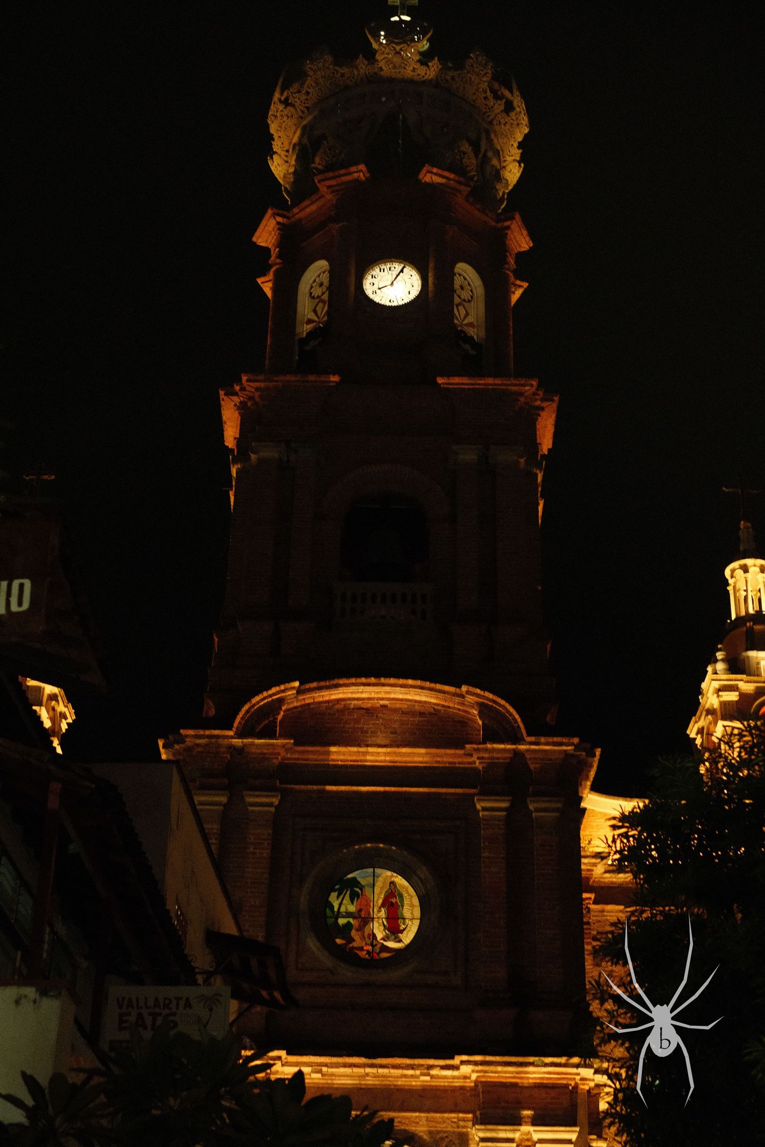 Illuminated church bell tower photographed at night with dramatic lighting.