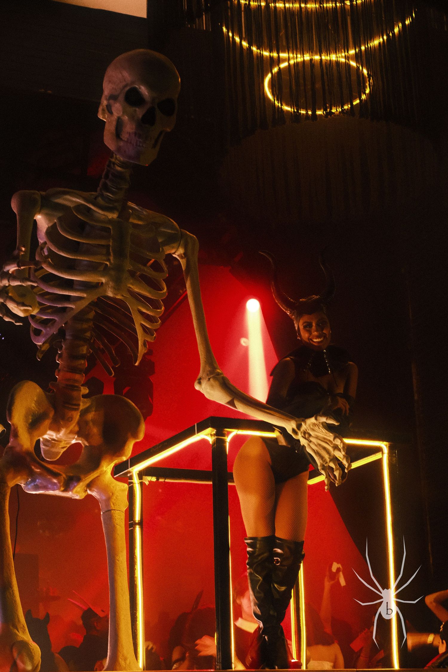 Decorative skeleton prop lit by red lights and string lighting in dark setting.