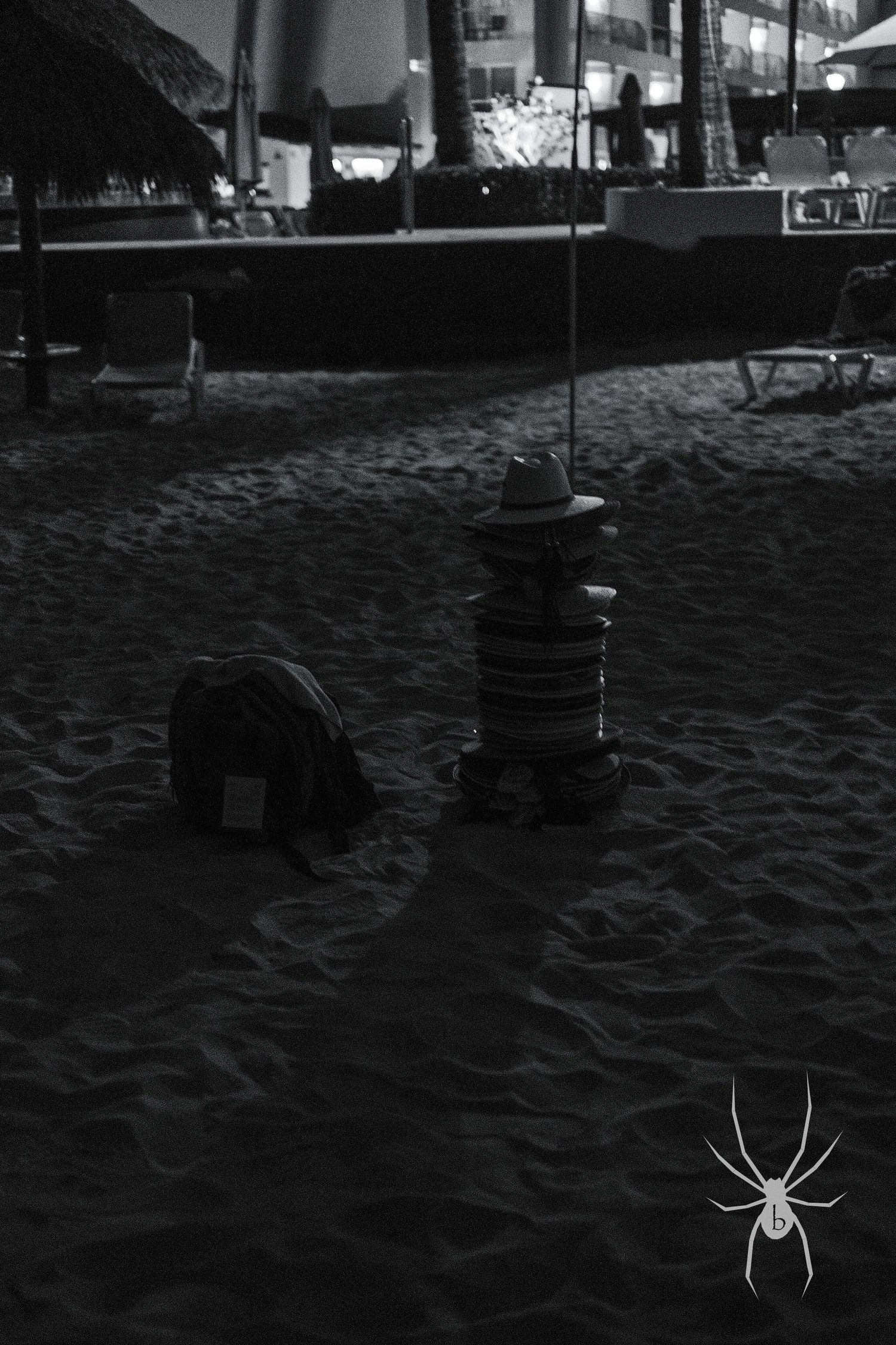 Dark nighttime beach scene with objects casting shadows on sandy ground.
