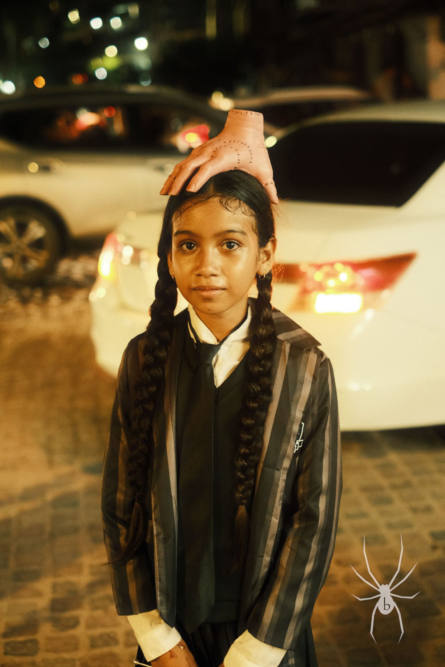 Young student in formal attire posing at night under street lights.
