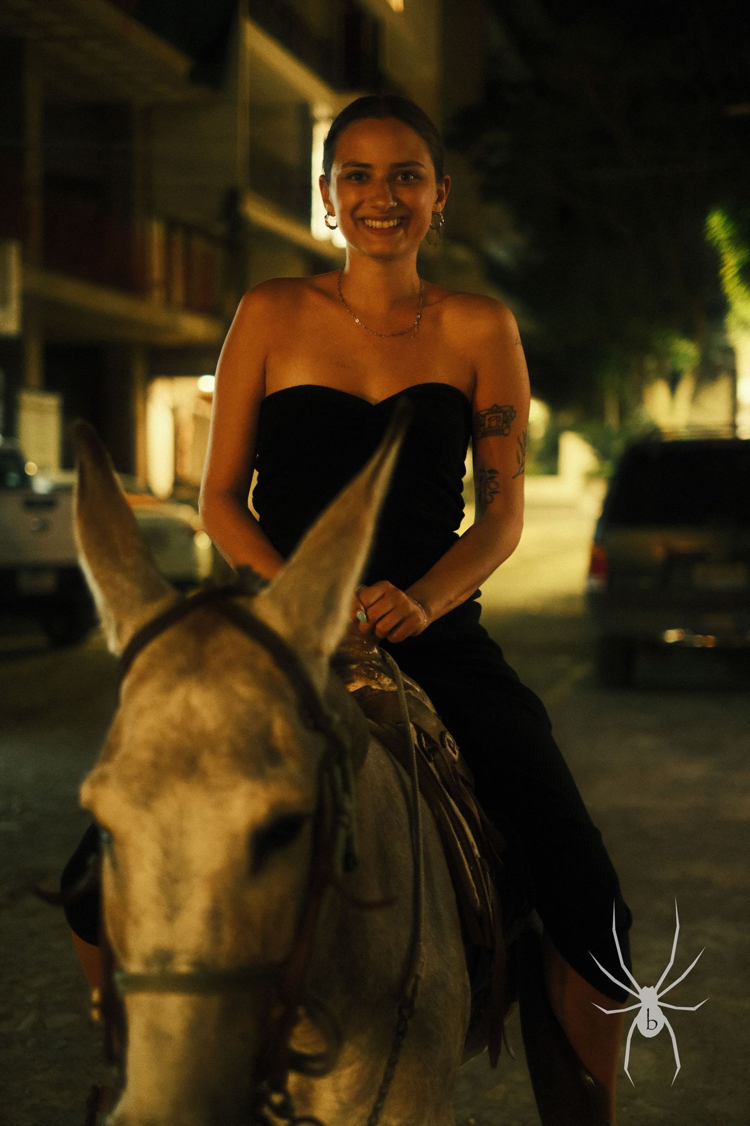 Person riding a horse at night wearing a black formal dress.