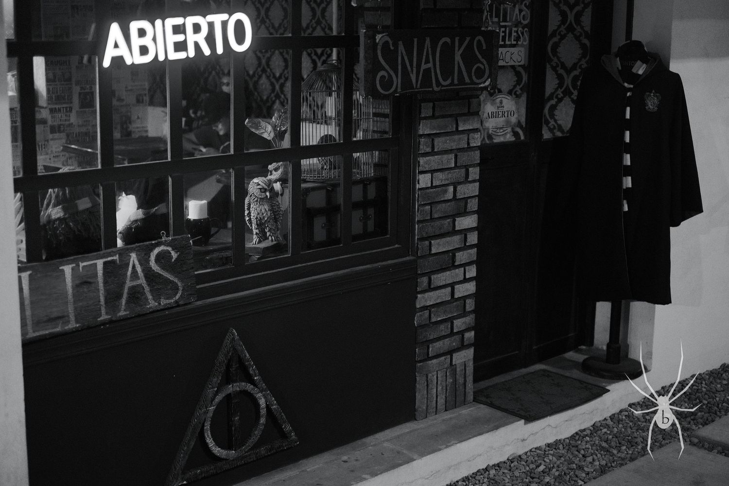 Dark storefront with neon 'Abierto' sign and hanging clothing in window display.