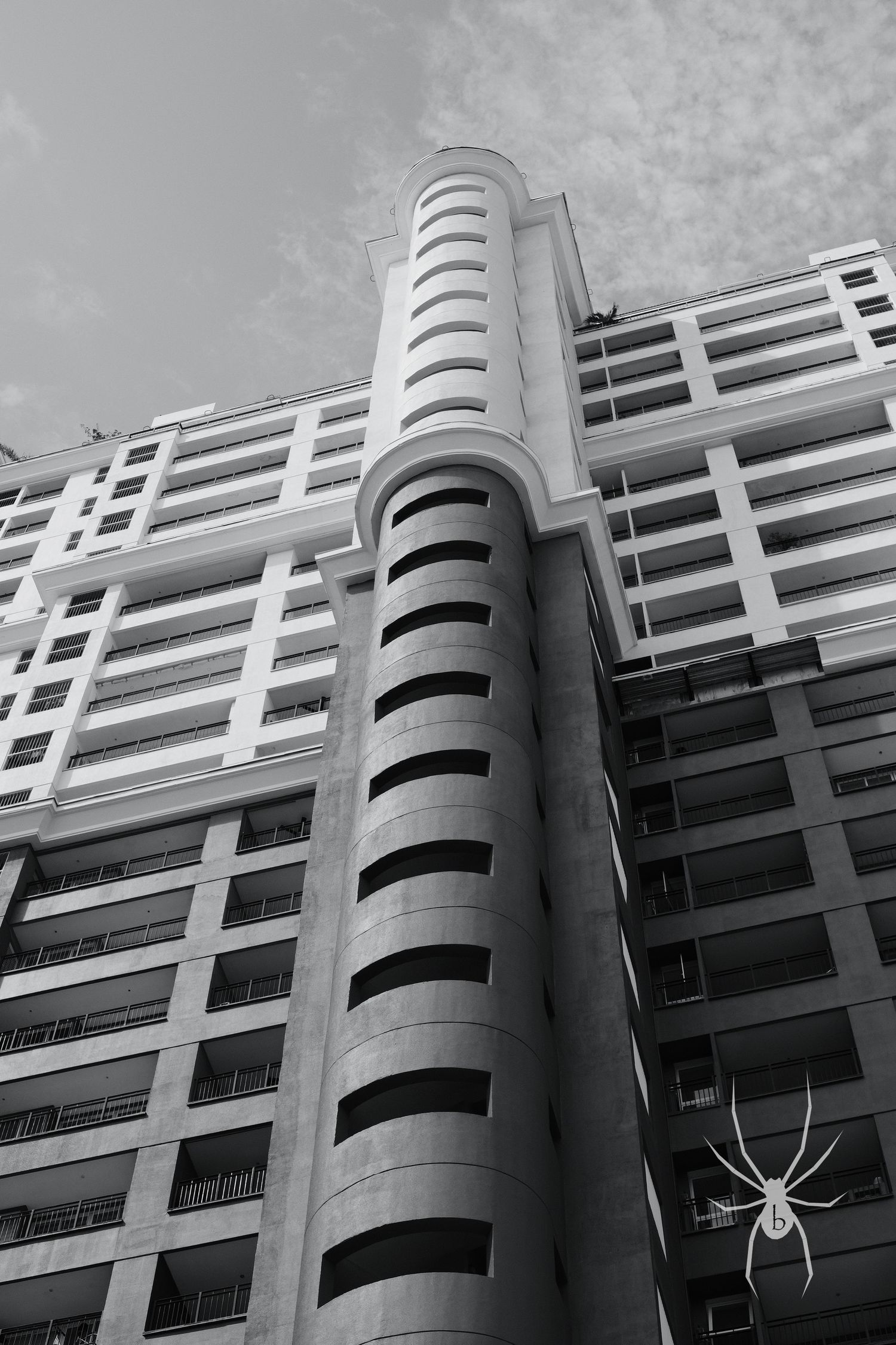 Modern high-rise building with distinctive curved architectural features photographed in black and white.