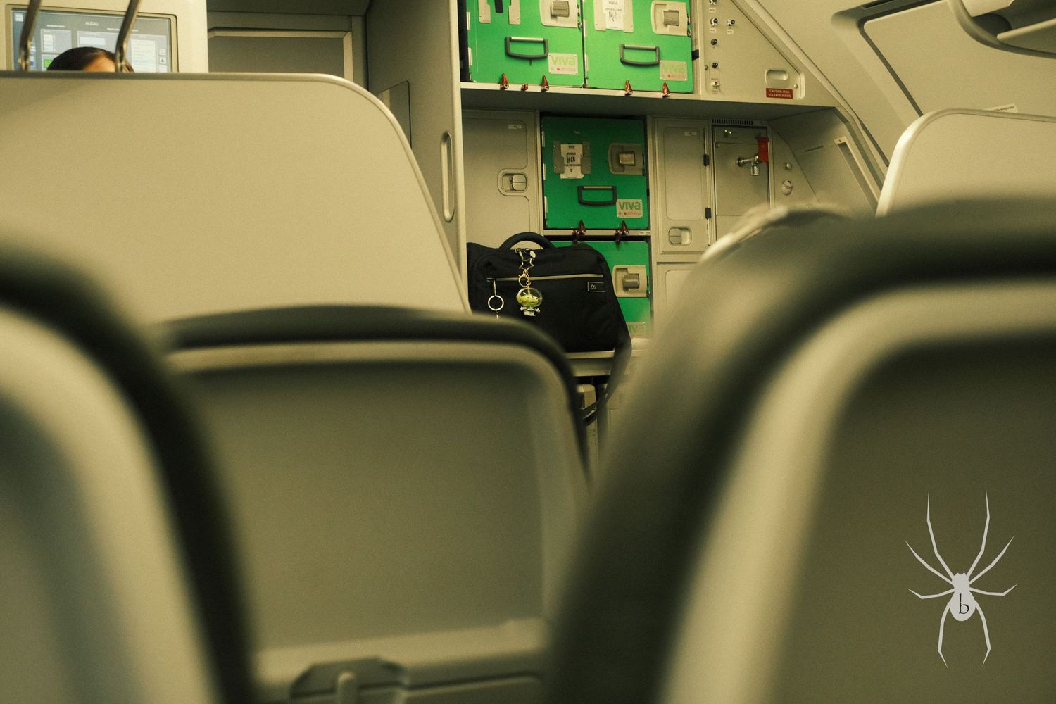 View between bus seats looking towards the front with a green exit sign visible.