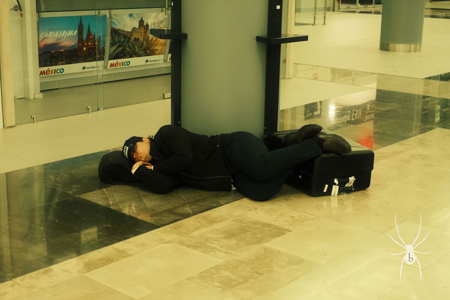 Person sleeping on the floor of what appears to be an airport terminal.