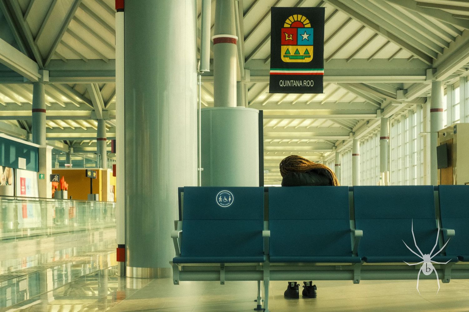 Empty airport terminal waiting area with blue seats and a spider overlay.