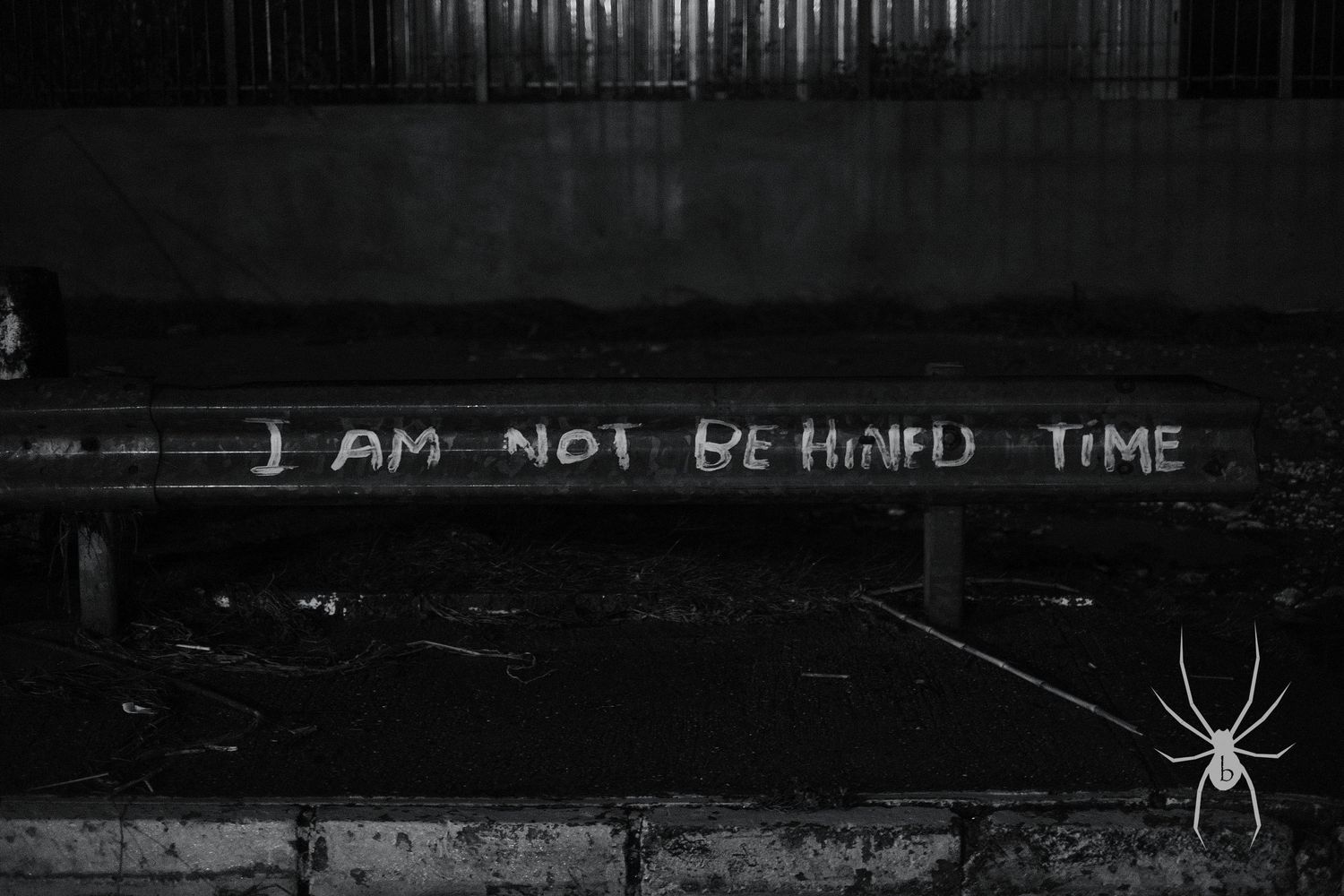 Dark graffiti on a concrete wall with a spider silhouette overlay.