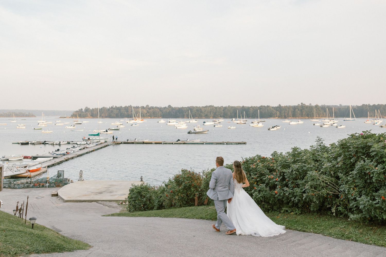 Scenic waterfront view with boats anchored in the harbor and a white tent on the shore.