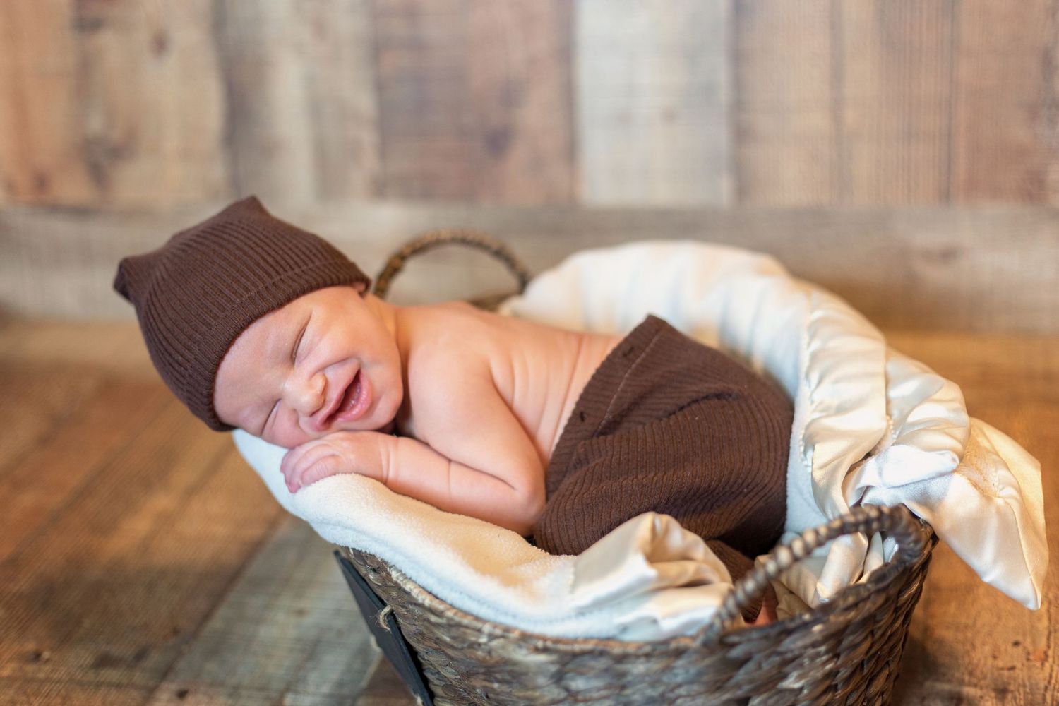 Newborn baby sleeping peacefully on a soft brown blanket during a professional photo session.