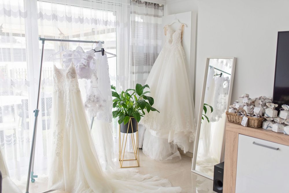 Bridal boutique interior with multiple wedding dresses and full-length mirror.