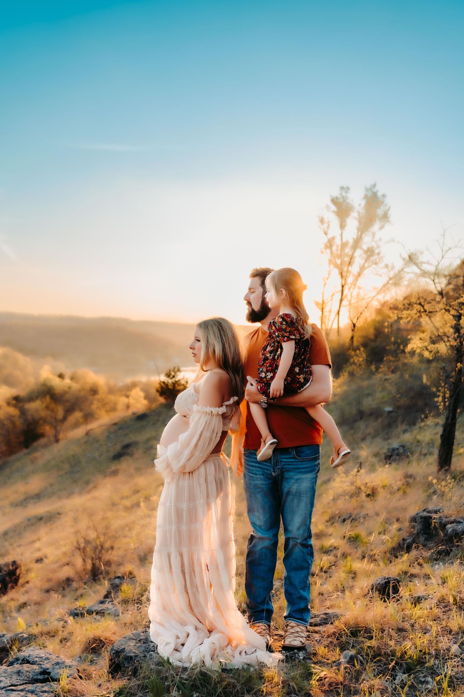 A sunset engagement photo shows a couple embracing on a golden hillside.