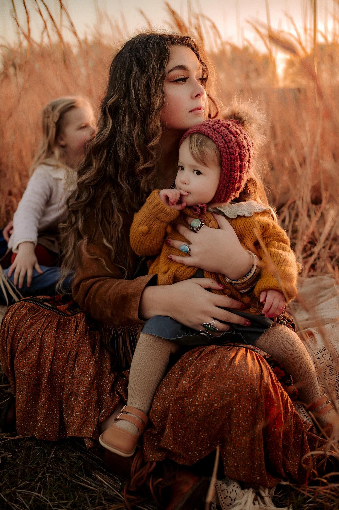 Intimate family portraits in golden sunlight among autumn grass and pumpkins.
