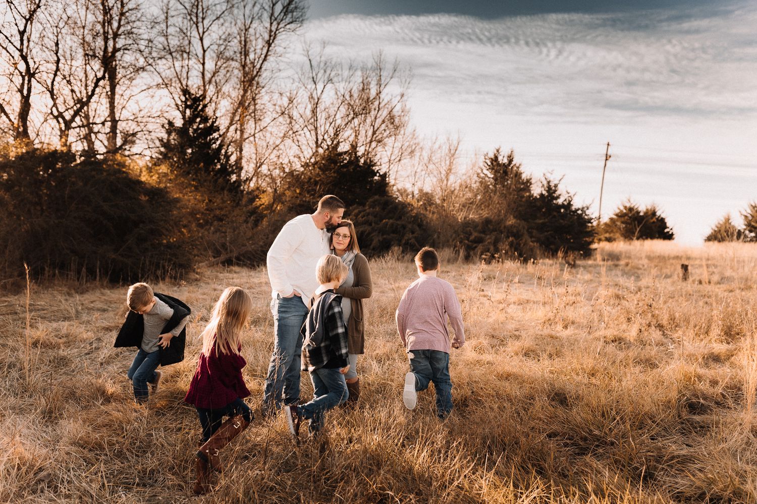 Family with children walking together in a golden field during a beautiful autumn sunset.