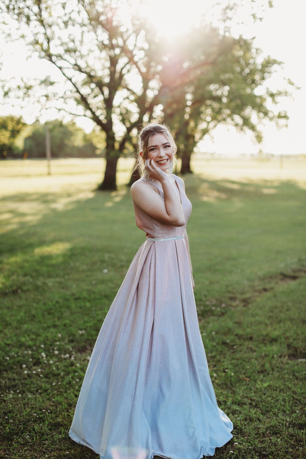 Elegant long formal dress with ombre effect from pink to blue photographed at sunset in a grassy field.