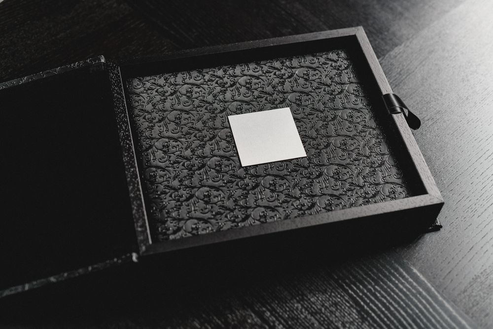 An open black photo box with decorative pattern and white label.