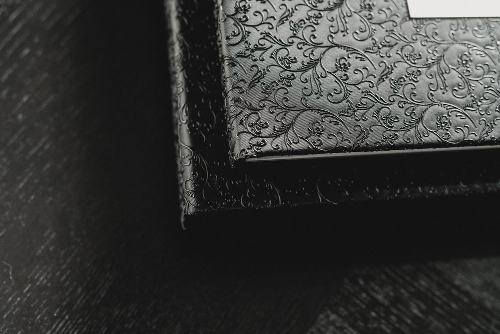 Corner detail of a black textured photo album with ornate embossed design.
