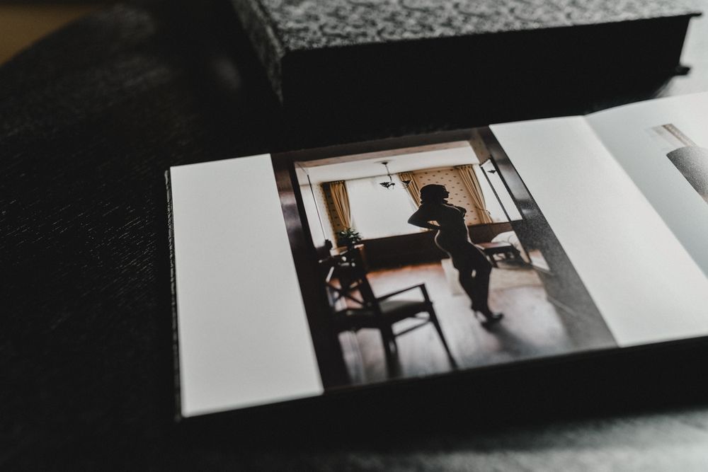 A photograph in an elegant black album showing a silhouetted figure by a window.