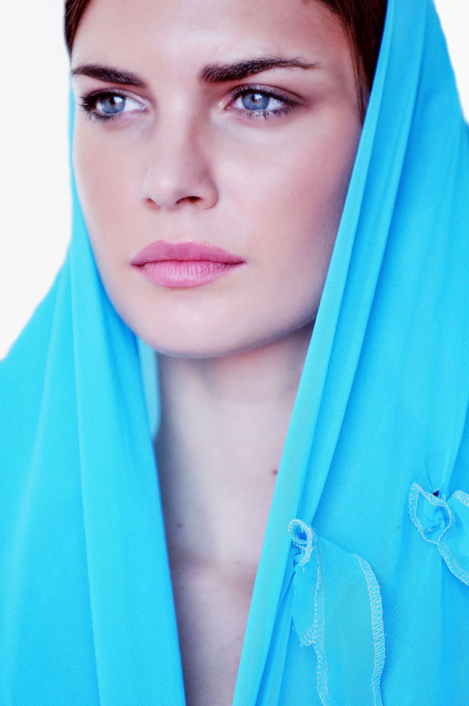 Fashion portrait with bright turquoise headscarf and intense gaze.