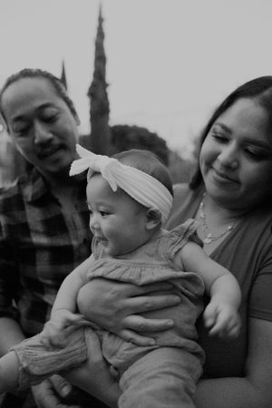 Black and white family portrait with baby wearing bow headband.