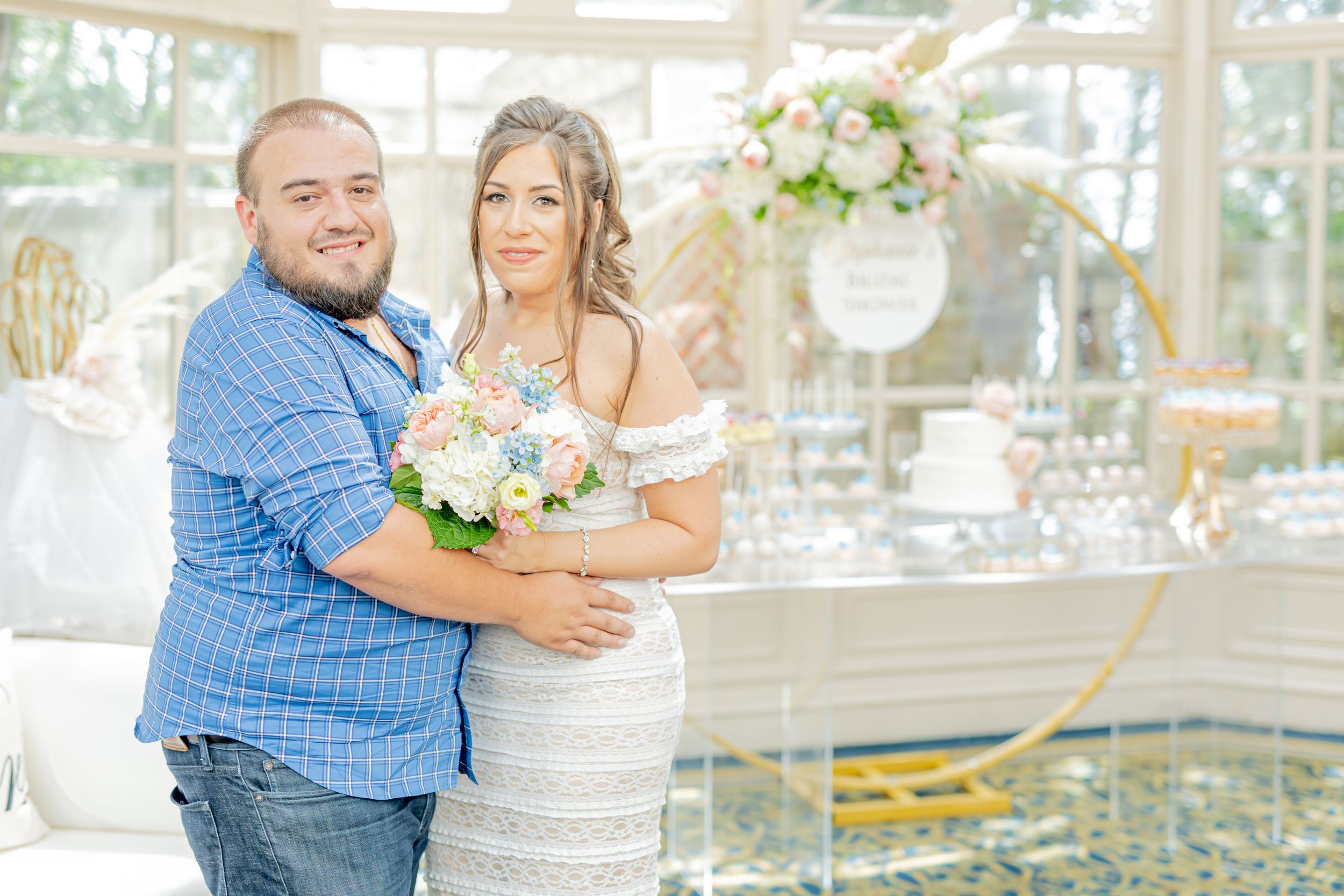 Wedding couple poses together in bright conservatory setting with floral decorations.