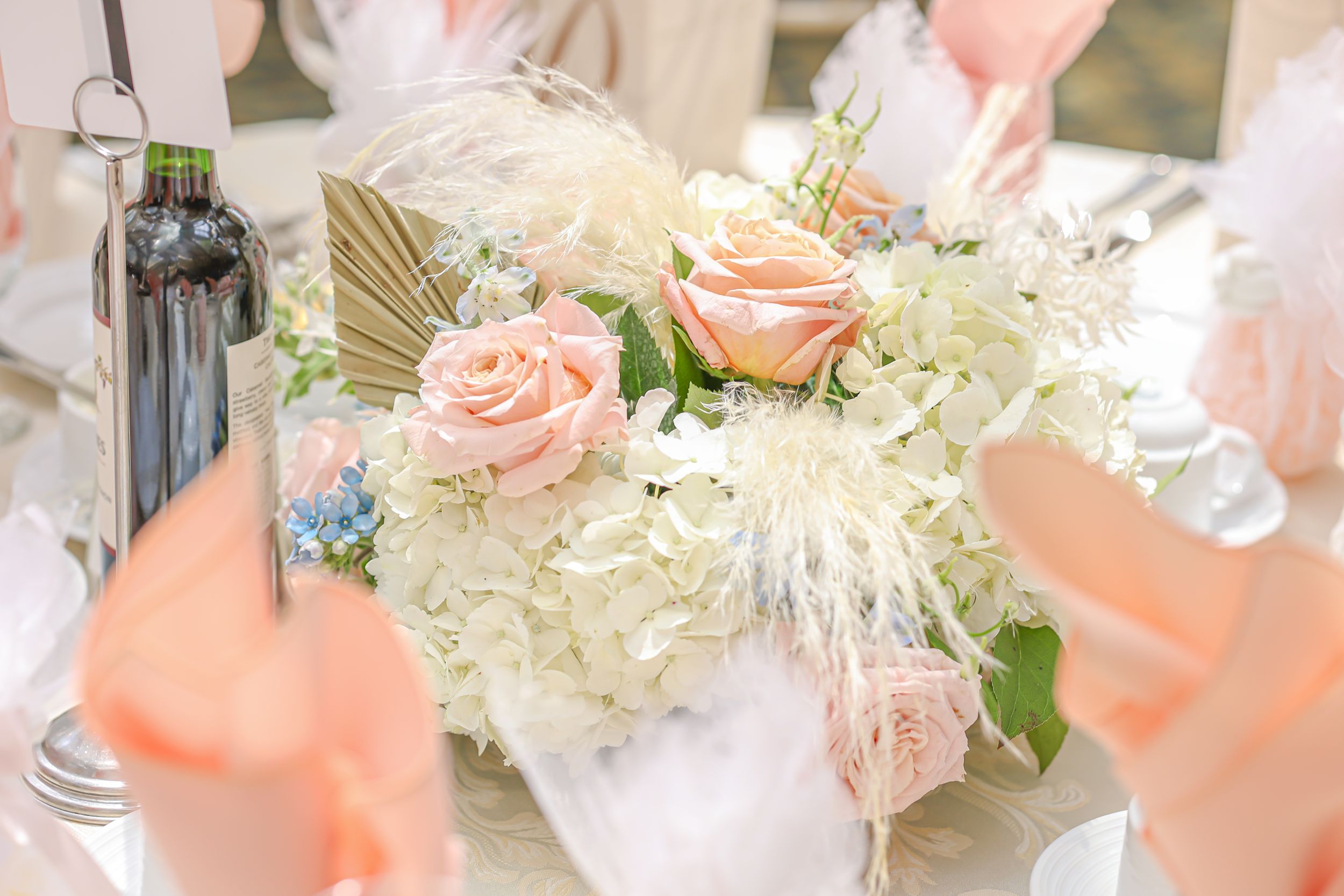 Elegant wedding centerpiece with pink roses and white hydrangeas in soft lighting.