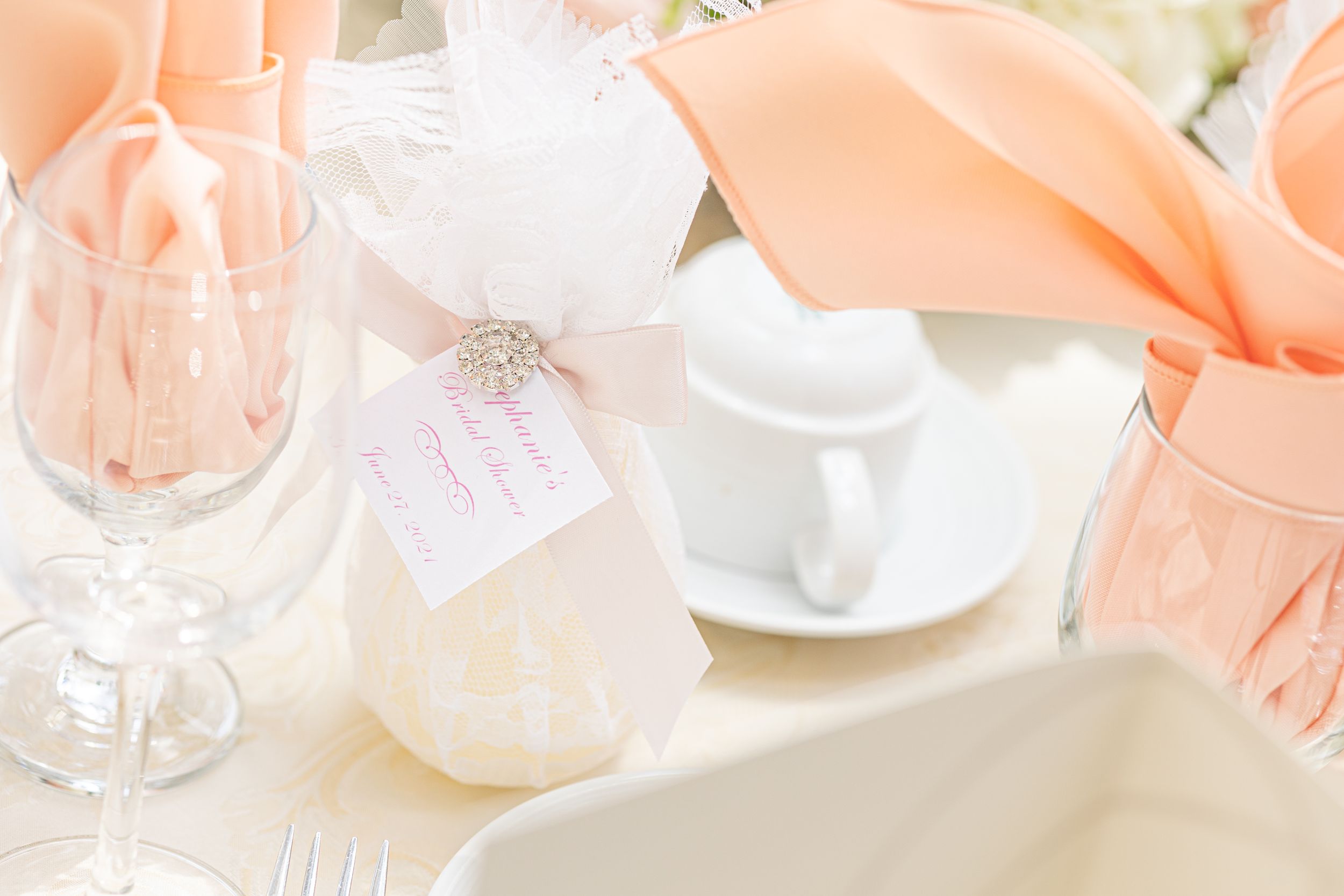 Soft peach and white table setting with delicate tags and crystal glassware.