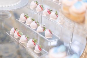 Pink and white chocolate covered strawberries elegantly displayed on clear acrylic trays.