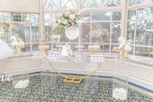 Elegant conservatory room with gold and white dessert displays and patterned blue carpet.