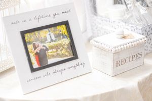 A white recipe box and photo frame displayed on a table with soft natural lighting.